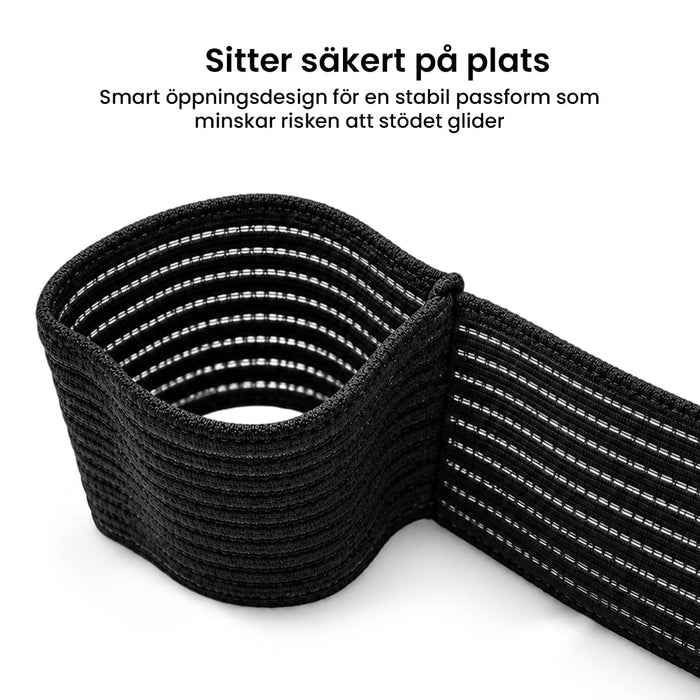 Musta joustava kyynärtuki, jossa on valkoinen sauma, kuvassa silmukka-asennossa valkoista taustaa vasten.